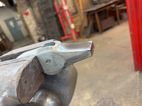 The hammer head is held in a vise with the cross peen facing out. It is much less crooked